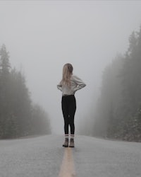 a woman standing on a foggy road